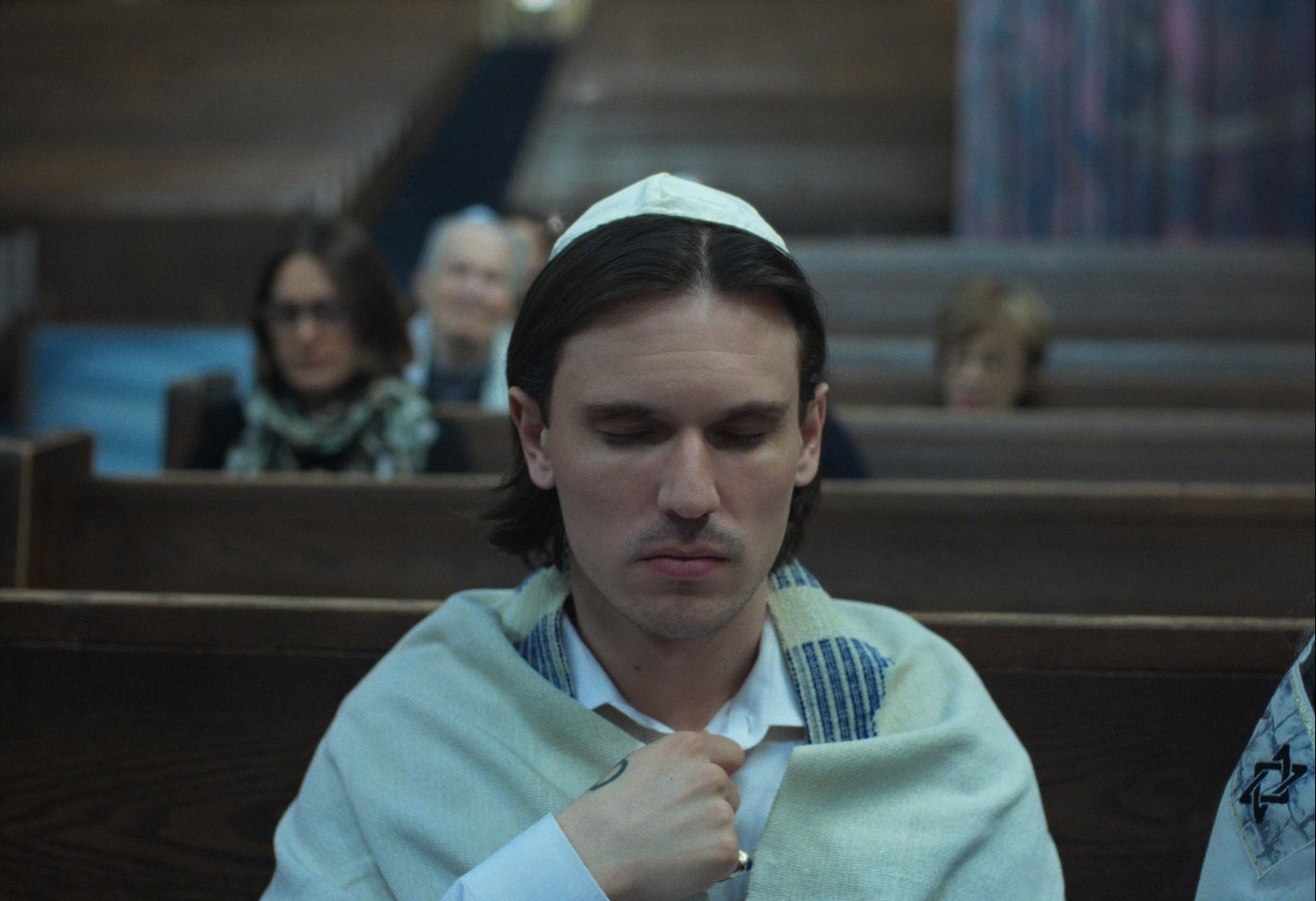 Joseph in a prayer shawl in a synagogue pew.